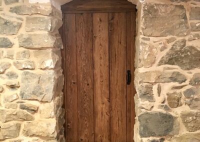 reclaimed mushroom boards used for a custom door fitted inside stone archway