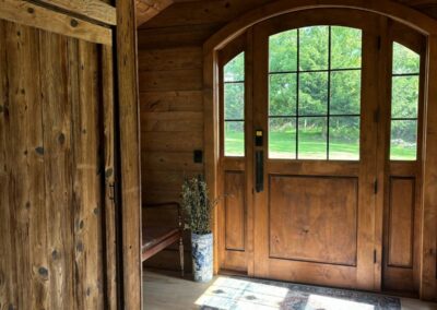 reclaimed mushroom boards used for wall paneling, custom ceiling and door in a home entryway